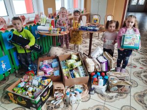 Dzieci stoją wokół darów zebranych dla Ukrainy.