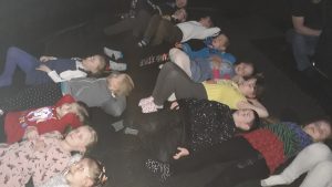 Na zdjęciu widać dzieci leżące na plecach, oglądające film wyświetlany wewnątrz kopuły kina sferycznego.