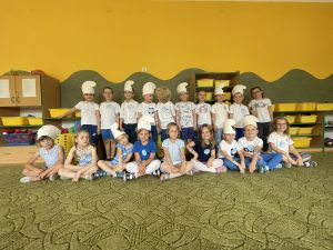Na zdjęciu widać grupę dzieci w czapkach smerfów i ubranych na biało niebiesko